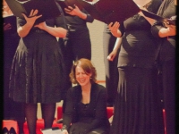 Chorus members stand and sit on the floor laughing during sound check before the concert.